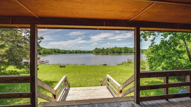 Terraza de madera con vista a un lago y vegetación circundante.