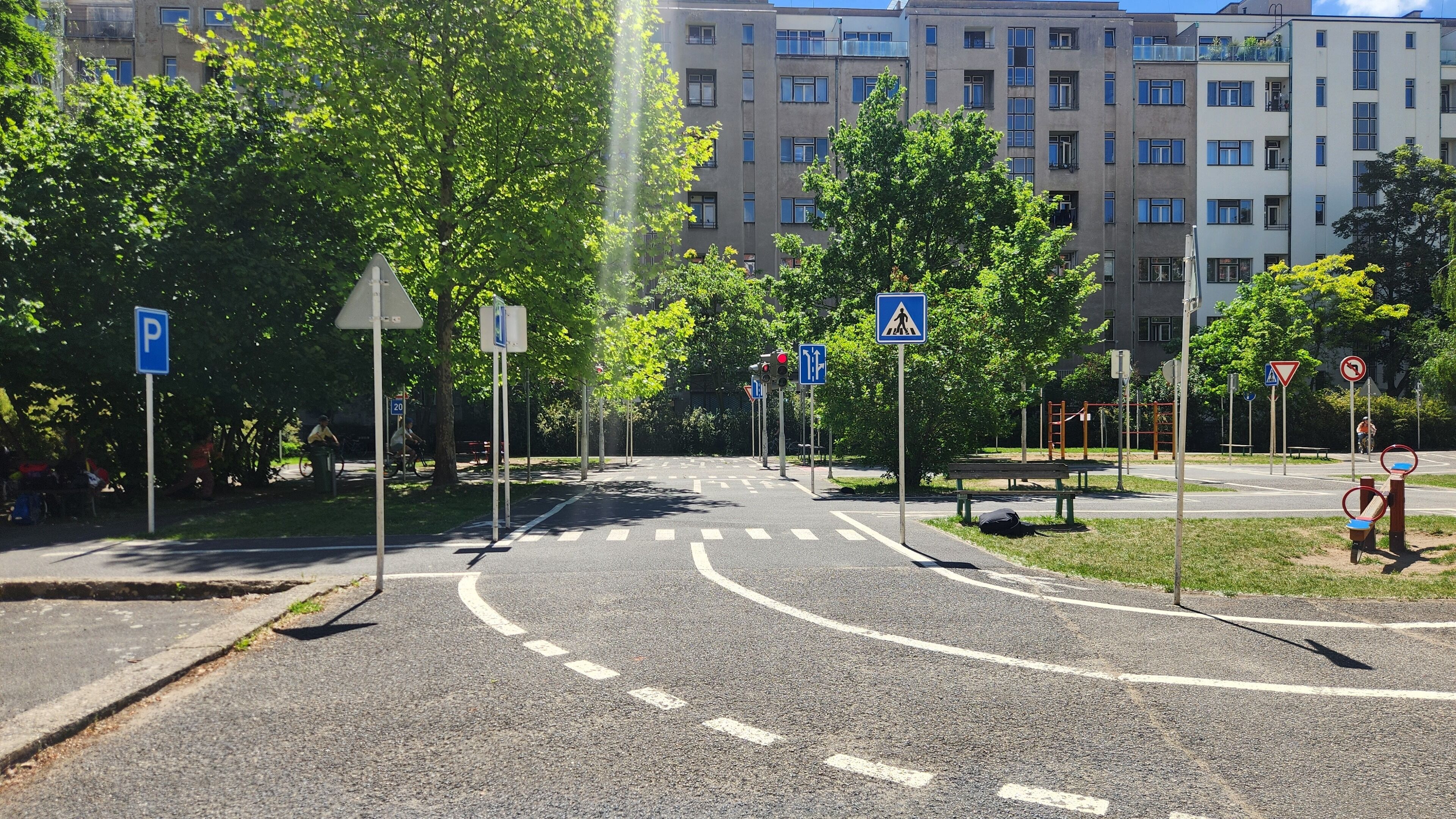 A multi-lane road with a pedestrian crossing, a parking sign, and a speed limit sign.