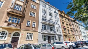 A row of multi-story buildings with various architectural styles, including a white building with balconies and a brown building with a corner entrance. - Apartment in Clouds Letná Luxury Balcony (Prague)