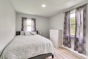 Une chambre à coucher avec un lit, une commode et une fenêtre avec des rideaux.