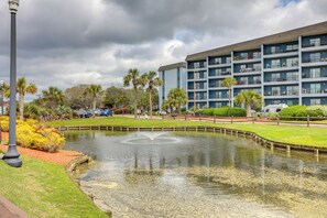 Een hotel met een waterpartij, een parkeerplaats en een meerlaags gebouw met balkons.