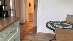 A kitchen with a coffee maker, a dining table with a patterned tablecloth, and a painting on the wall. - Apartment 'Ehemaliges Gutsverwalterhaus' with Shared Terrace, Shared Garden and Wi-Fi (Woldegk OT Mildenitz)