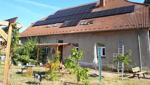 A house with a tiled roof, solar panels, a wooden deck, and a small garden. - Apartment 'Ehemaliges Gutsverwalterhaus' with Shared Terrace, Shared Garden and Wi-Fi (Woldegk OT Mildenitz)