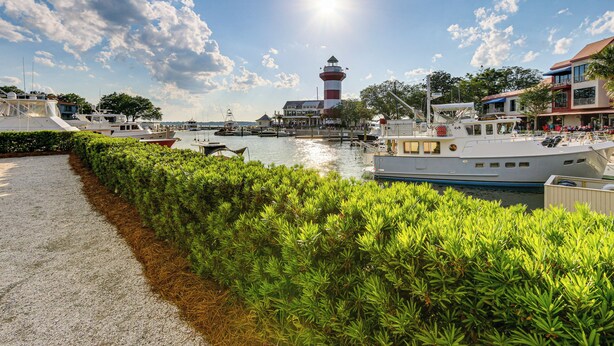 A marina with boats docked, a lighthouse, and buildings with balconies overlooking the water. - Walk to Harbour Town: Quaint Sea Pines Gem (Hilton Head Island)