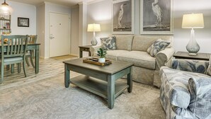 A living room with a sofa, coffee table, and a dining area with chairs and a table. - Walk to Harbour Town: Quaint Sea Pines Gem (Hilton Head Island)