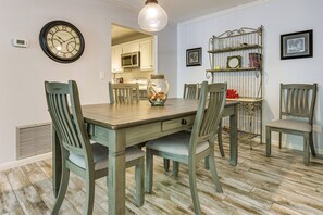 Une salle à manger avec une table en bois, des chaises, une horloge et un vase rempli de coquillages.