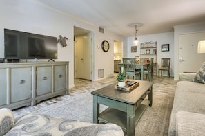 A living room with a television, a coffee table, and a sofa. There is a dining area with chairs and a table. - Walk to Harbour Town: Quaint Sea Pines Gem (Hilton Head Island)
