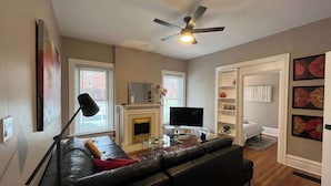 Una sala de estar con chimenea, televisor, sofá y ventilador de techo.