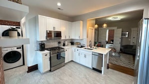 A modern kitchen with white cabinets, stainless steel appliances, and a built-in oven.