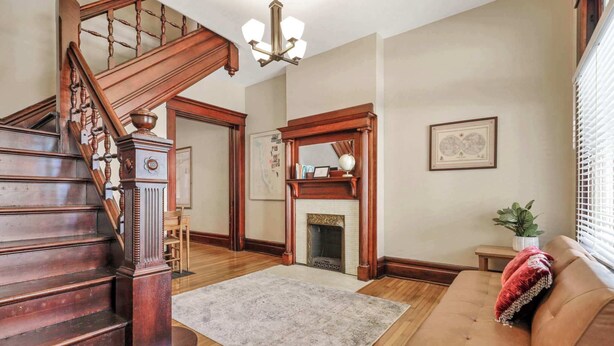 A spacious living room with a wooden staircase, a fireplace, and a cozy seating area. - 4 Bed 2 Bath Townhouse - Goodale Park (Columbus)