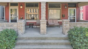 A building with two numbered doors, 127 and 129, a covered porch with stone columns, and a bench. - 4 Bed 2 Bath Townhouse - Goodale Park (Columbus)