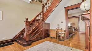 A wooden staircase with a decorative handrail, a wooden desk with a chair, and a globe on a shelf. - 4 Bed 2 Bath Townhouse - Goodale Park (Columbus)