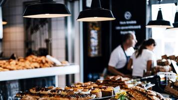 Une vitrine de boulangerie présentant diverses pâtisseries et des lampes suspendues noires.