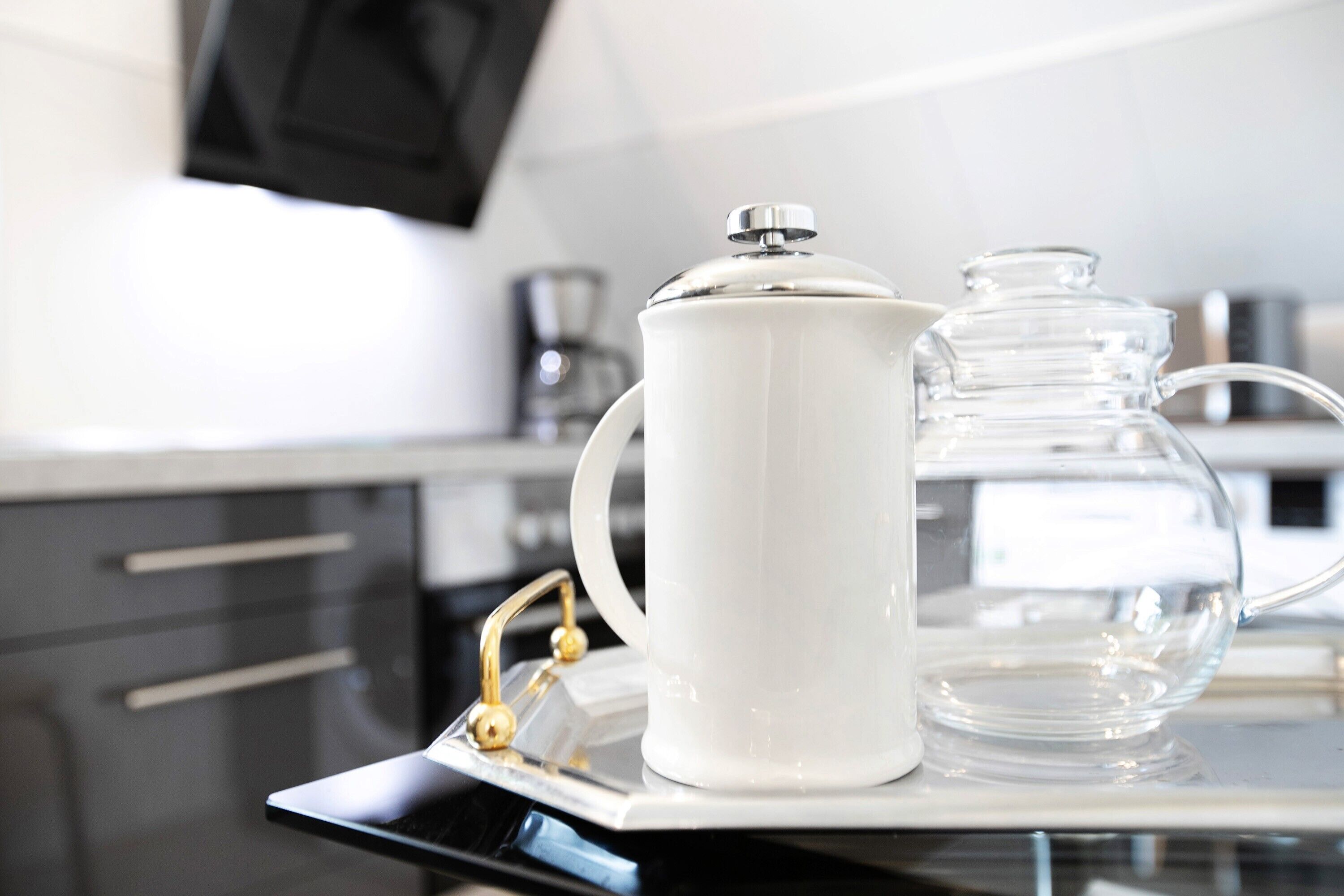 A white ceramic pitcher and a glass carafe on a tray.