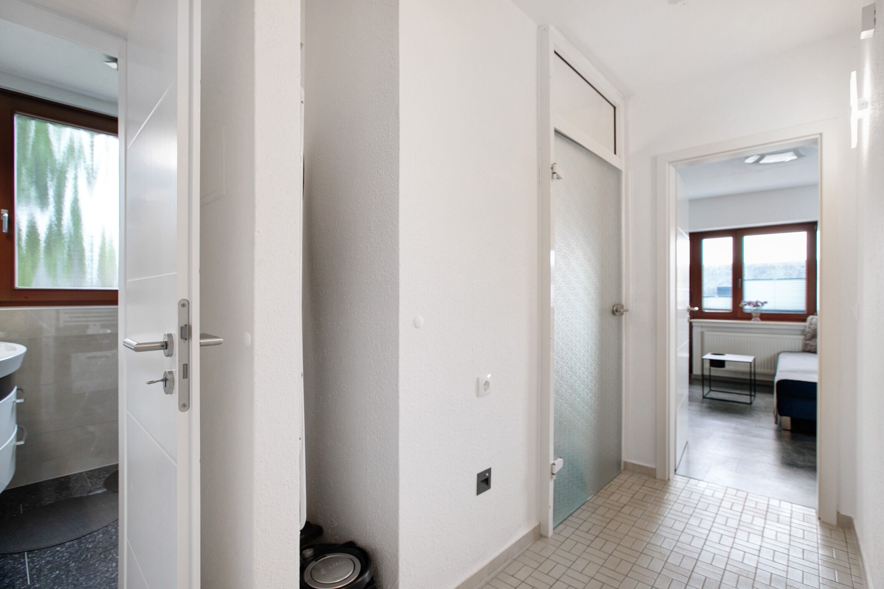 Ein Flur mit Toilette, einer Tür und einem Fenster, das in ein Schlafzimmer führt.