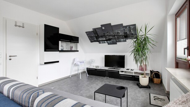 Una sala de estar moderna con un sofá, una mesa de centro, un televisor y una planta grande en maceta.
