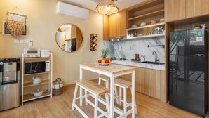 A modern kitchen with wooden cabinets, a black refrigerator, a marble countertop, and a wooden dining table with stools. - 2BR Private Pool Villa Dove By Orivista (Mengwi)