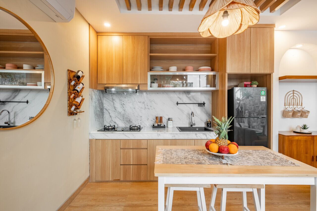 A modern kitchen with wooden cabinets, a marble countertop, and a dining area with a table set for two.