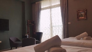 A hotel room with two beds, a chair, a desk, a TV, and a window with curtains. - Venice (Taitung)