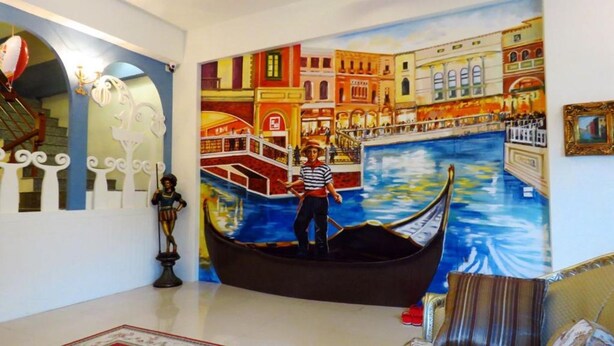 A room with a mural of a gondola on a canal, a statue, and a framed picture on the wall. - Venice (Taitung)
