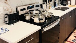 Een moderne keuken met houten kastjes, een rvs fornuis, een inbouwoven en een wit aanrecht.