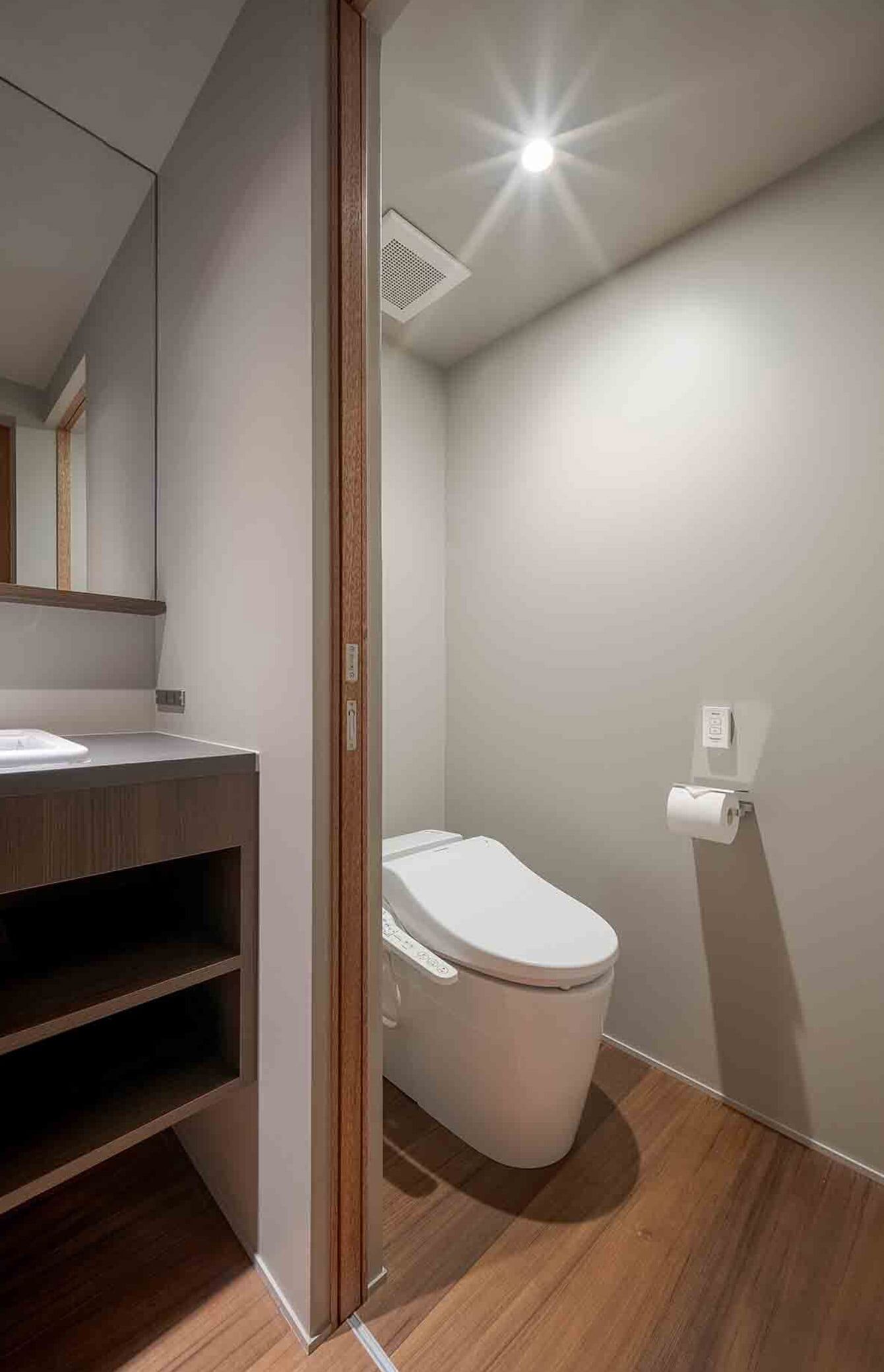Une salle de bain moderne avec un meuble-lavabo en bois, des toilettes et une douche.