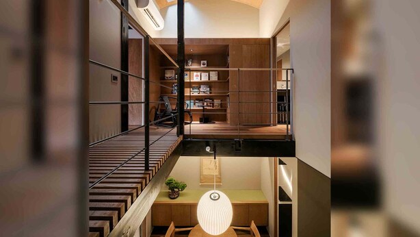 Un interior de varios niveles con una escalera, un comedor y una estantería empotrada.
