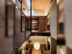 Un intérieur à plusieurs niveaux comprenant un escalier, un coin repas et une bibliothèque intégrée.
