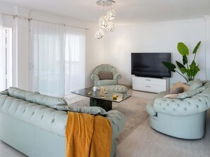 A modern living room with a sofa set, a coffee table, a television, and a large plant.