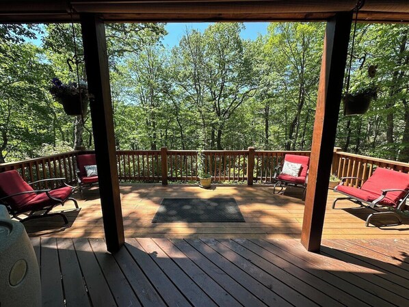 Une terrasse en bois avec des chaises rouges et un tapis au centre.
