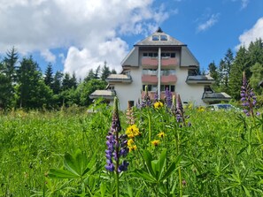 Un bâtiment doté d’un toit triangulaire, de balcons et d’une voiture garée devant.