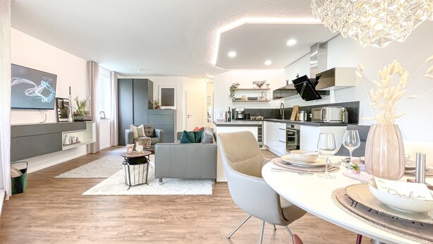 Uma sala de estar moderna com sofá, mesa de jantar e cozinha equipada.