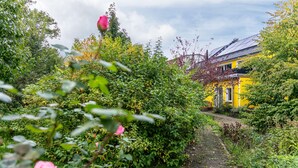 Um caminho no jardim leva a um edifício amarelo com um caminho de tijolos.