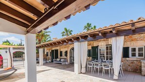 Un espace extérieur aménagé en terrasse, avec un sol en pierre, des meubles blancs et une structure en forme de pergola.