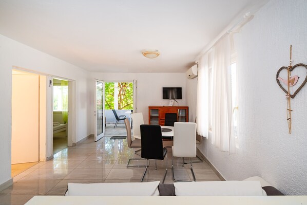 A modern living room with a dining area, a TV, and a heart-shaped decoration on the wall.