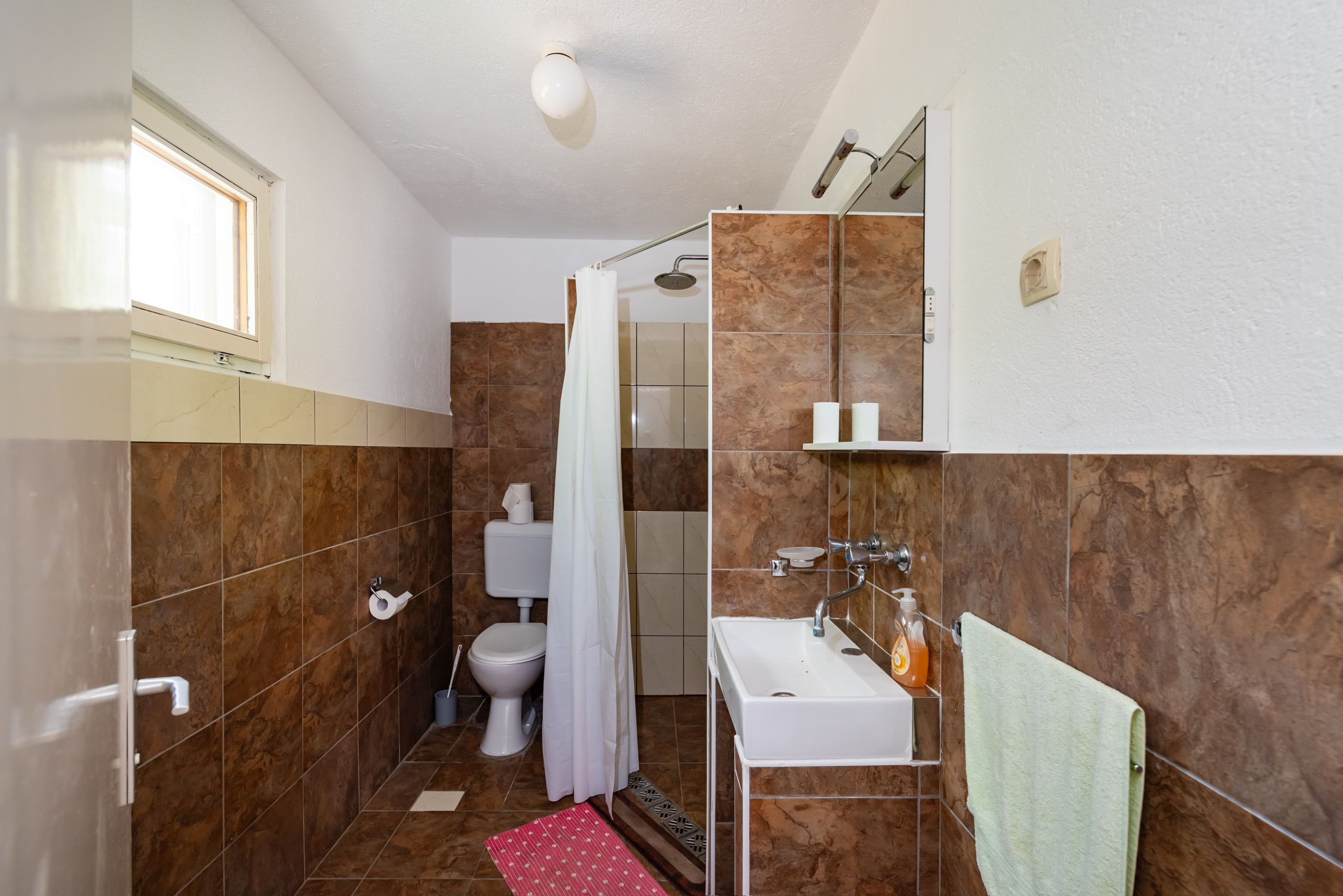 A bathroom with a shower, toilet, sink, and a towel rack.