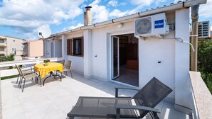 Une terrasse extérieure avec une table et des chaises, une porte-fenêtre coulissante et un climatiseur de la marque Haier.