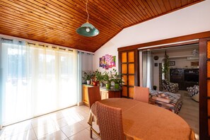 Un comedor con techo de madera, una mesa con sillas y vista a la cocina.