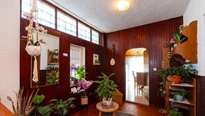 A room with wooden walls, a wooden staircase, a round table with a plant, and a bookshelf with plants.
