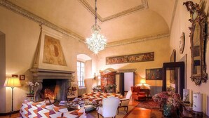 Una sala de estar amplia con chimenea, asientos cómodos y una araña.