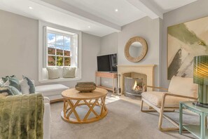 Ein Wohnzimmer mit Kamin, Fernseher, einem runden Holztisch und einer Couch.