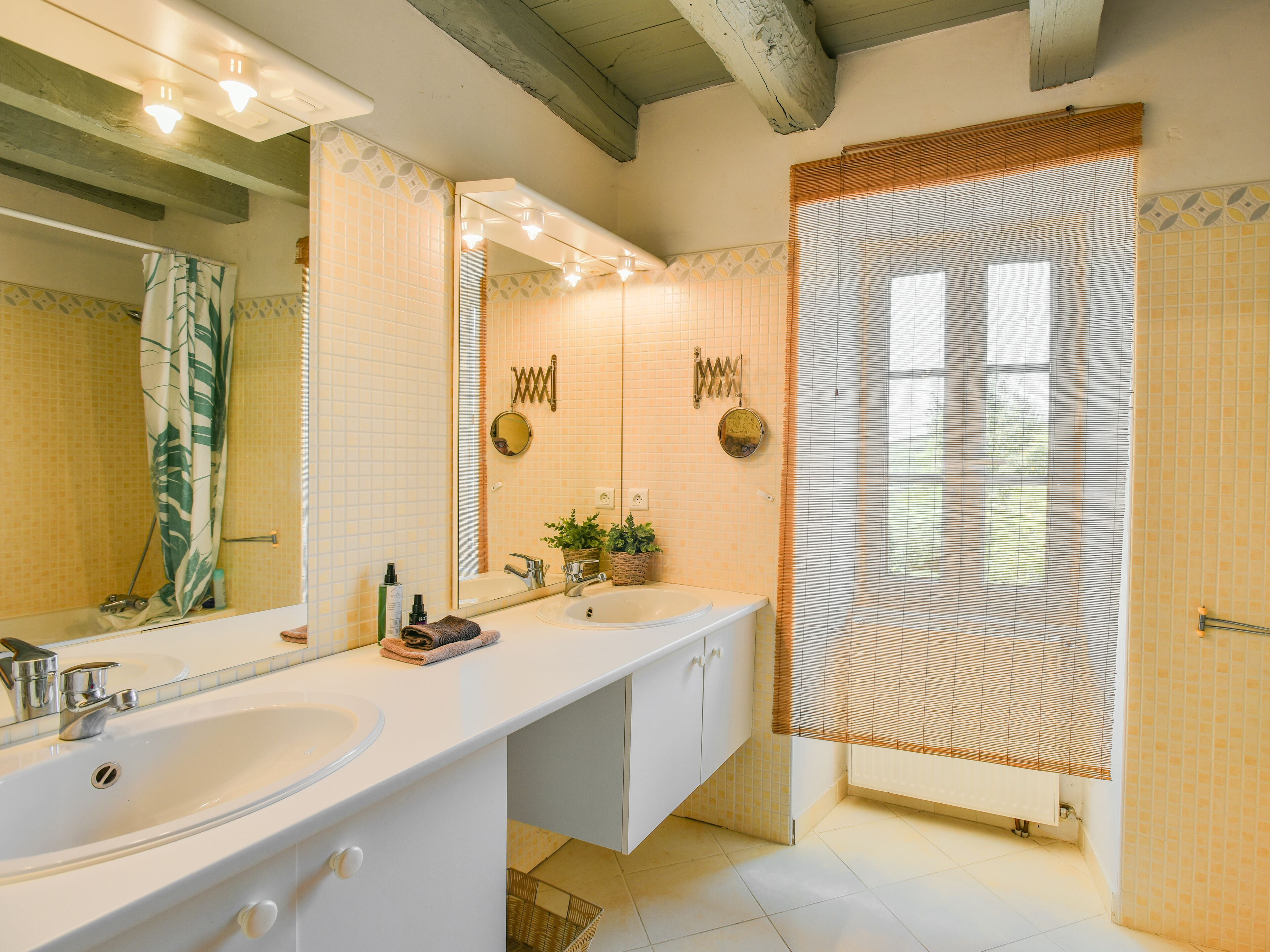 A bathroom with two sinks, a large mirror, and a shower with a window.