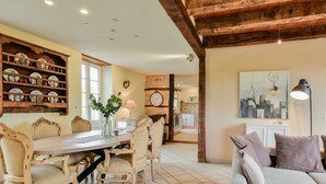 A dining area with a wooden table and chairs, a vase with flowers, and a kitchen in the background. - Beautiful holiday home with a shared pool (Dégagnac)