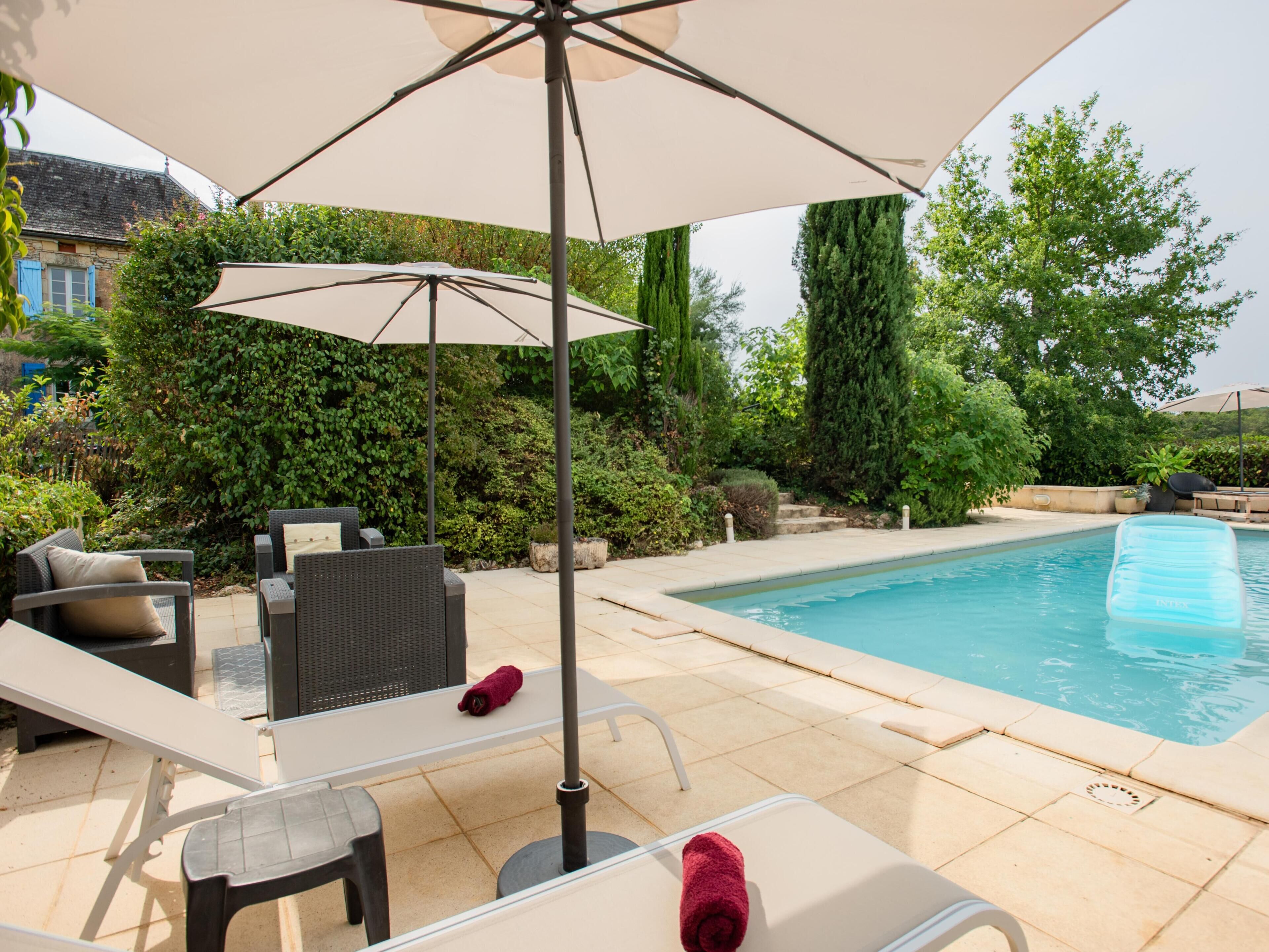 A poolside area with lounge chairs, a table, and an umbrella.