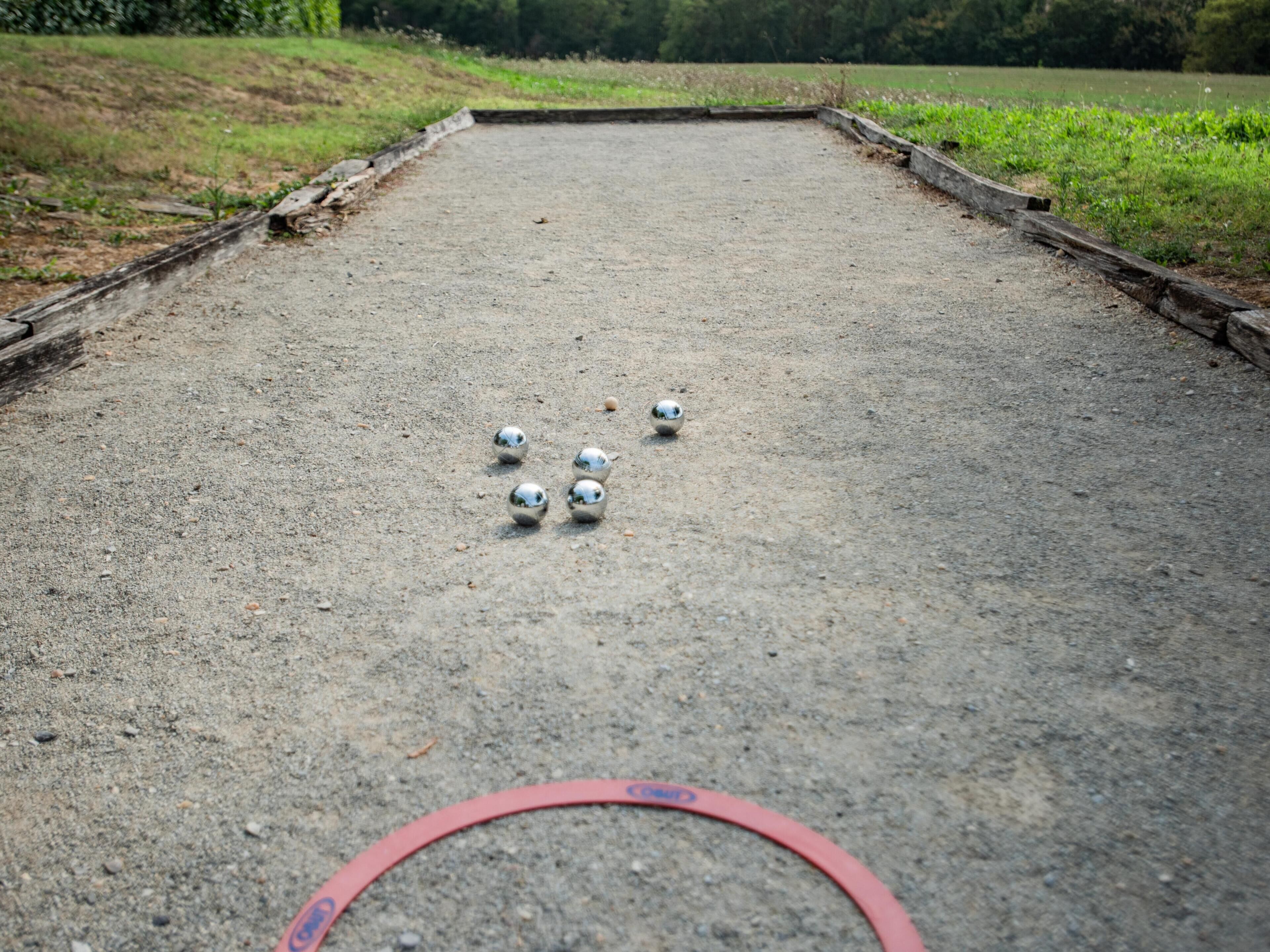 A croquet court with a red hoop and five metallic balls.