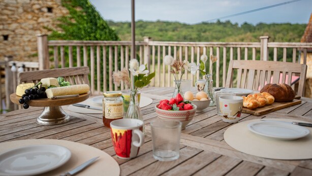 Una mesa de madera dispuesta con comida y bebidas, con vistas a un paisaje pintoresco.