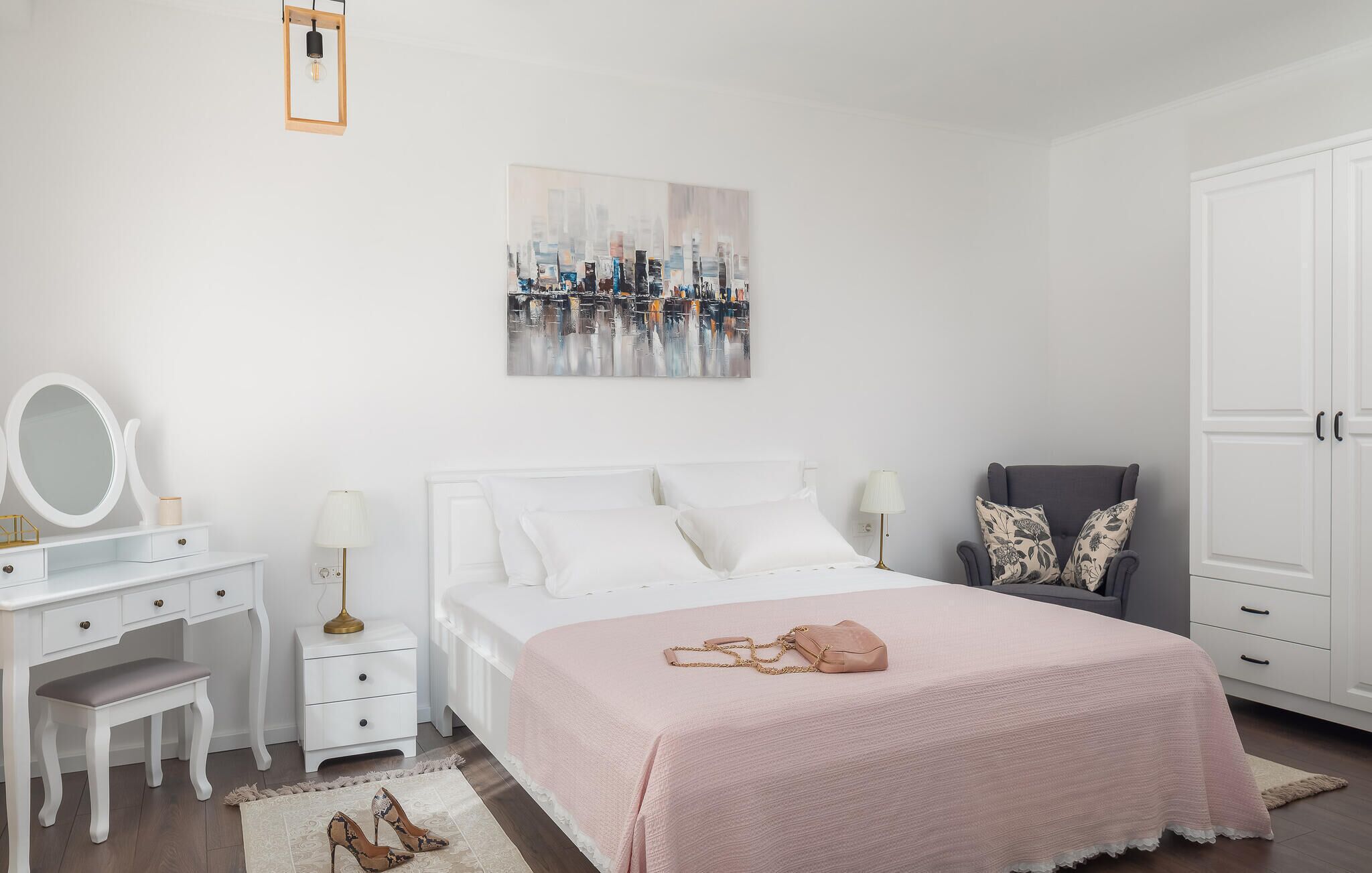 A bedroom with a bed, bedside tables, a dresser, a chair, and a painting on the wall.