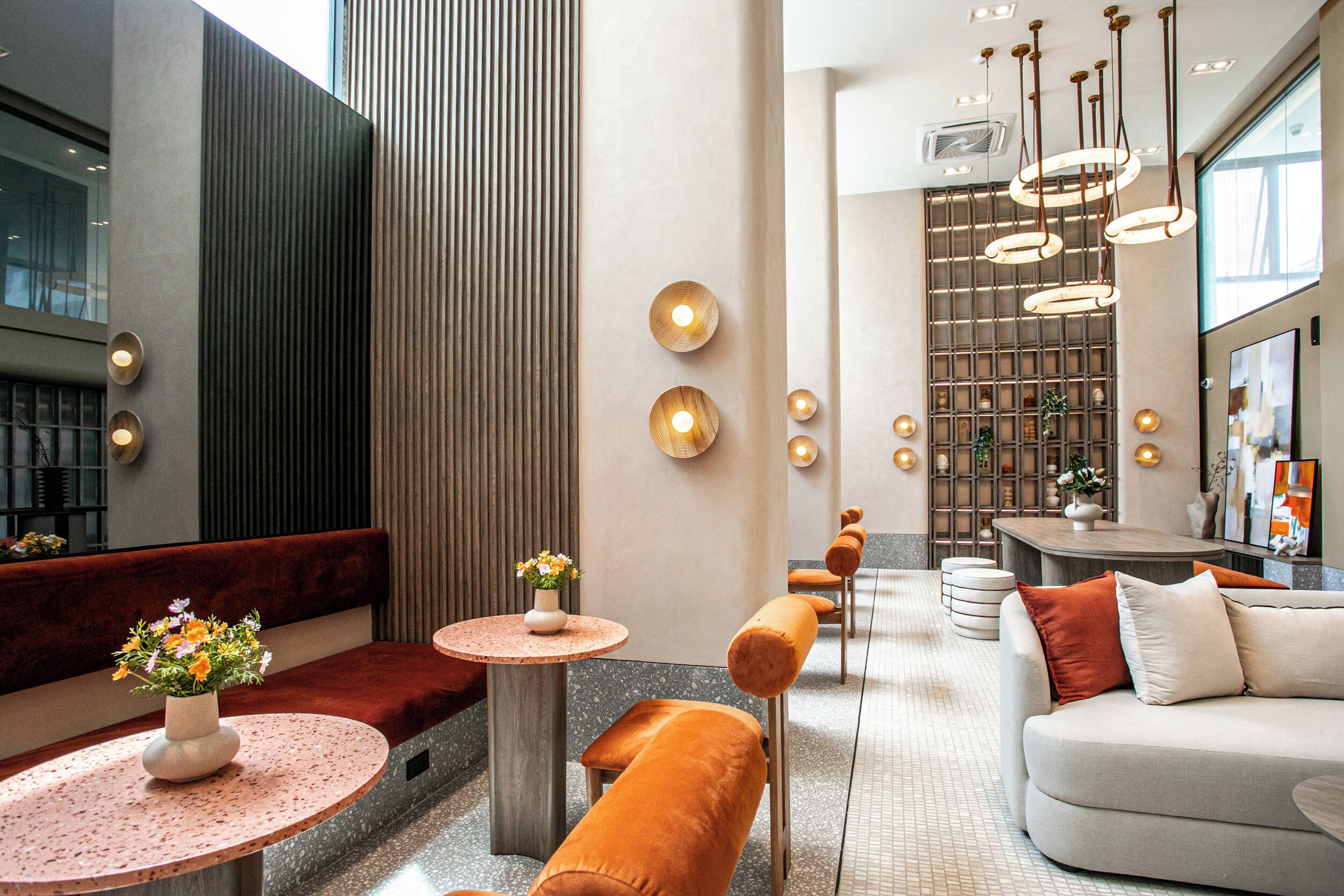 A modern interior with seating areas, a central column, and pendant lighting.