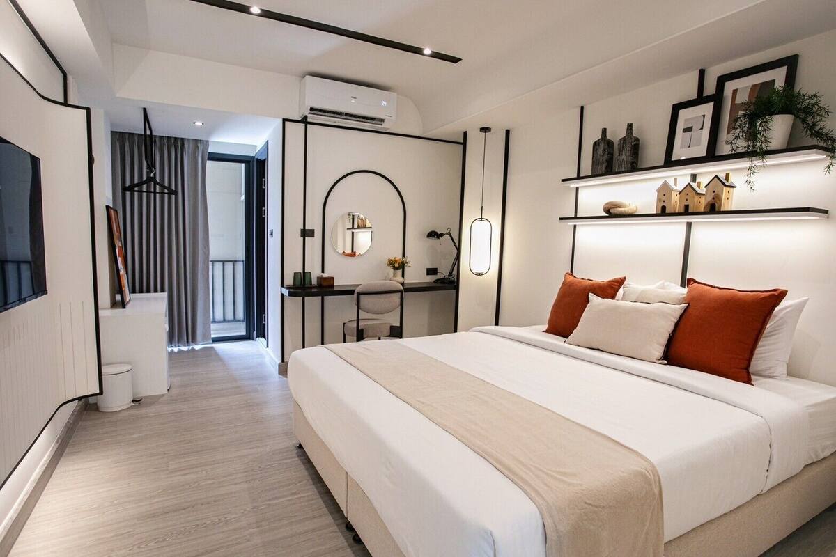 A modern bedroom with a large bed, bedside tables, a desk, and a hanging light fixture.