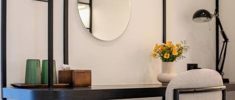 A modern room with a round mirror, a vase with flowers, and a chair.